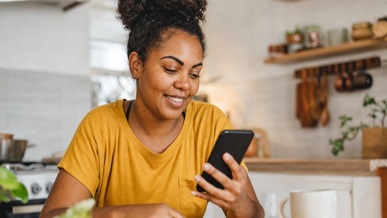Trabalhadora brasileira usando o celular para comparar Crédito do Trabalhador e cheque especial