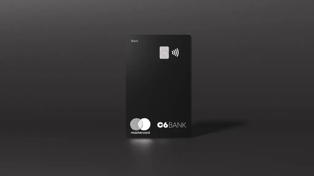 Cartão preto do C6 Bank em pé sobre fundo cinza escuro.