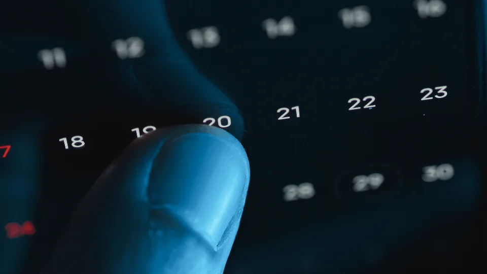 Dedo marcando o dia 20 no calendário, prazo da rotina mensal do RH