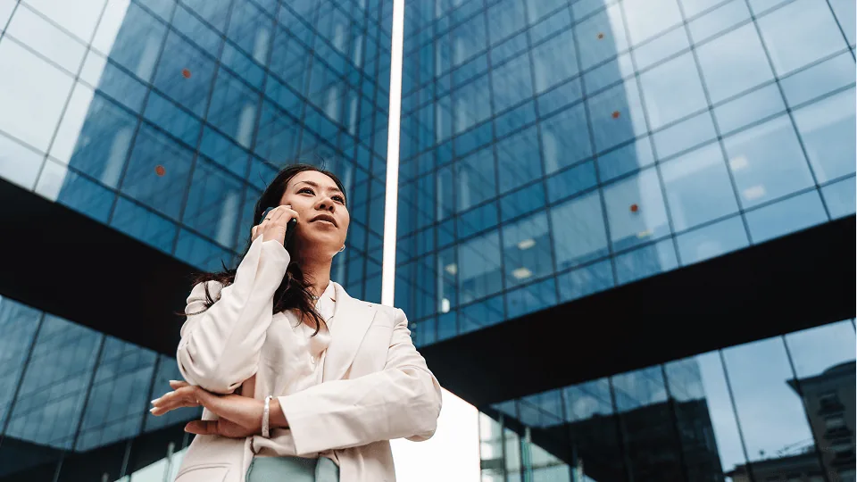 Gestora ao telefone diante de prédio comercial, representando a empresa no Crédito do Trabalhador