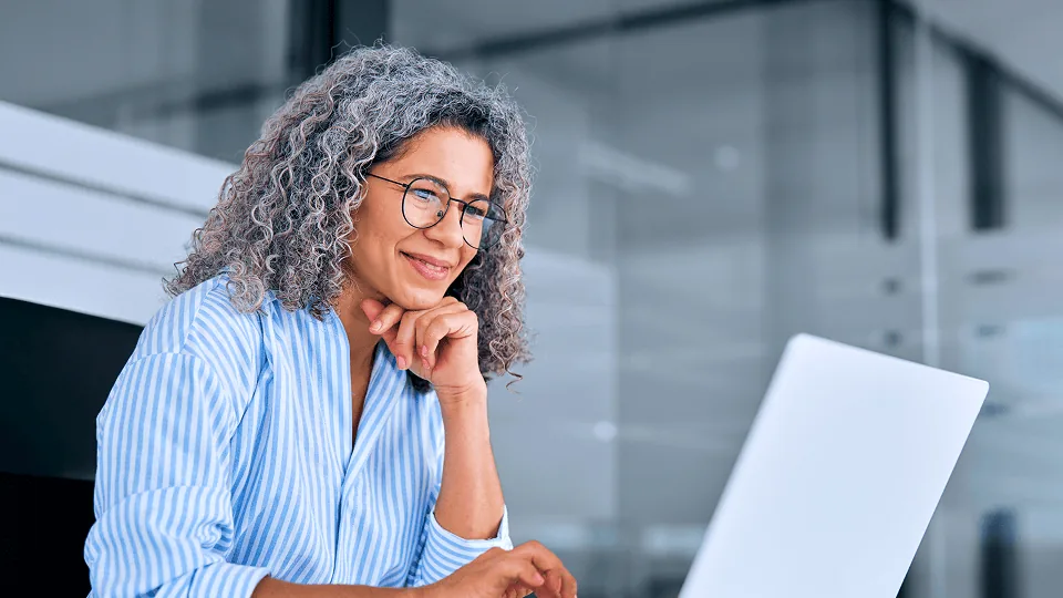 Profissional de RH sorrindo diante do notebook ao organizar a folha com consignado CLT