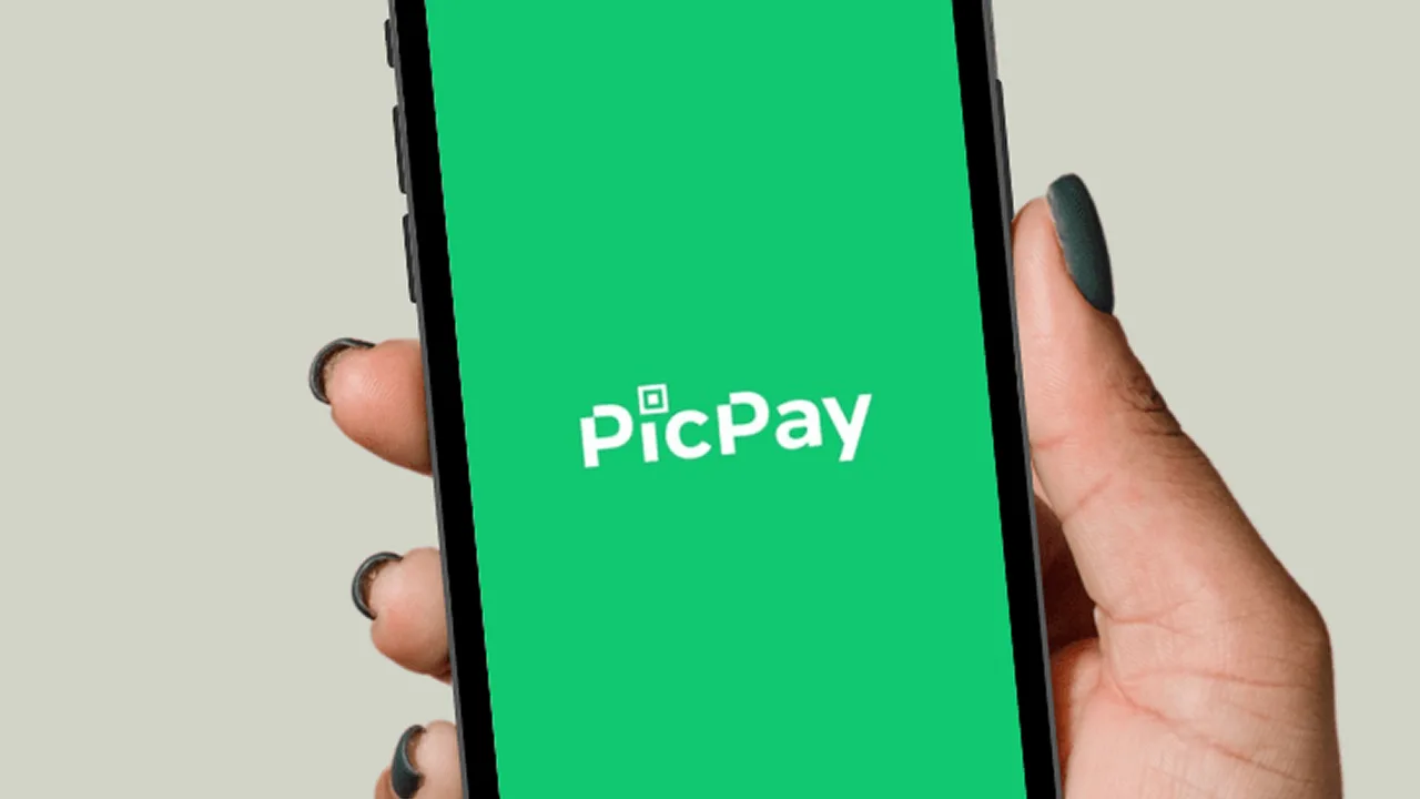 Mão segurando um celular com o logo do PicPay na tela.