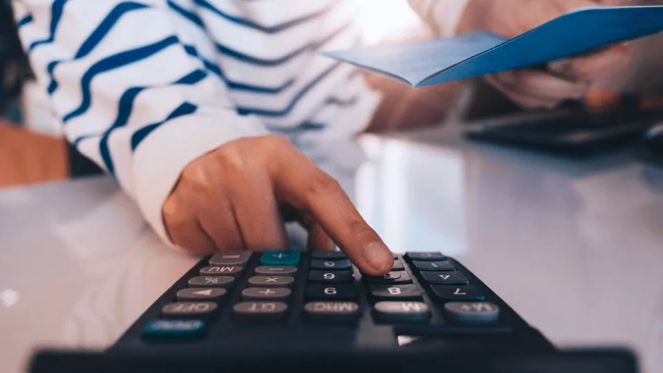 Pessoa usando calculadora para simular o refinanciamento do Crédito do Trabalhador