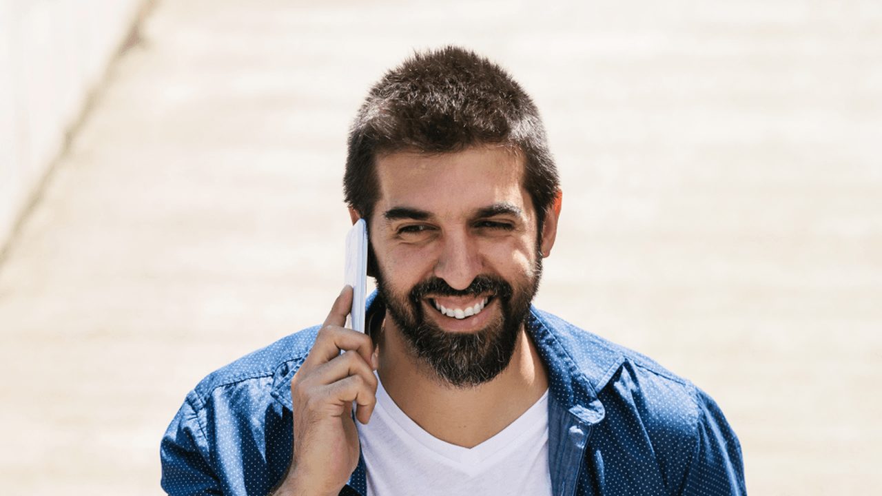 Trabalhador CLT sorri ao telefone enquanto tira dúvidas sobre empréstimo consignado para negativado