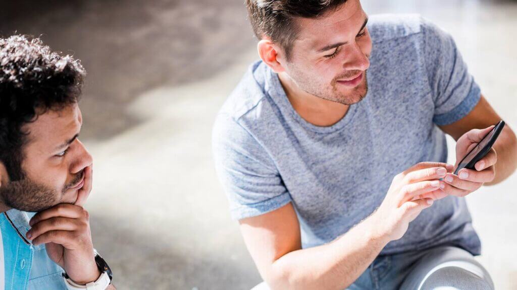 Dois homens conferindo informações no celular antes de contratar crédito