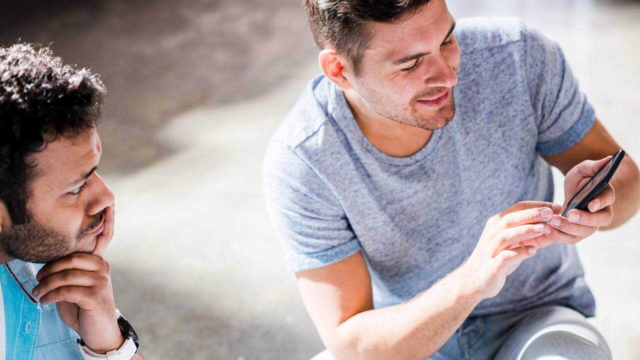 Dois homens conferindo informações no celular antes de contratar crédito